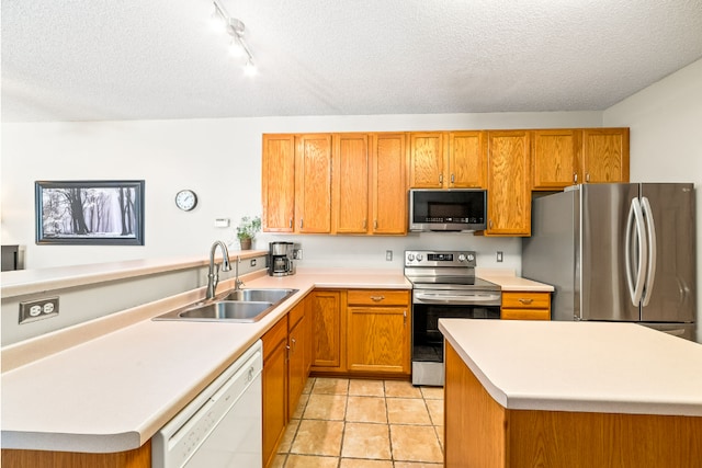 kitchen featuring a textured ceiling, light countertops, appliances with stainless steel finishes, and a sink