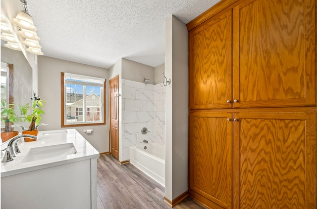 bathroom with a closet, shower / bathing tub combination, a sink, a textured ceiling, and wood finished floors