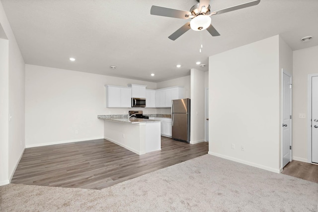 kitchen with a breakfast bar, white cabinetry, hardwood / wood-style floors, stainless steel appliances, and kitchen peninsula