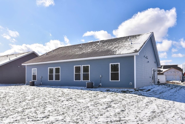 snow covered rear of property featuring central AC unit