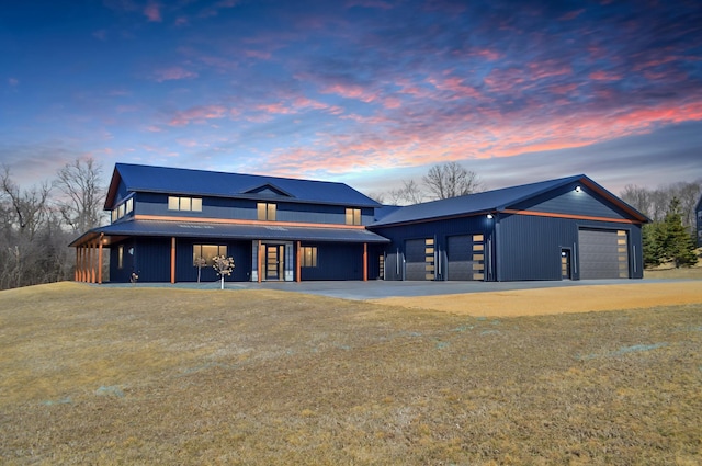 modern farmhouse style home featuring an outdoor structure, driveway, and metal roof