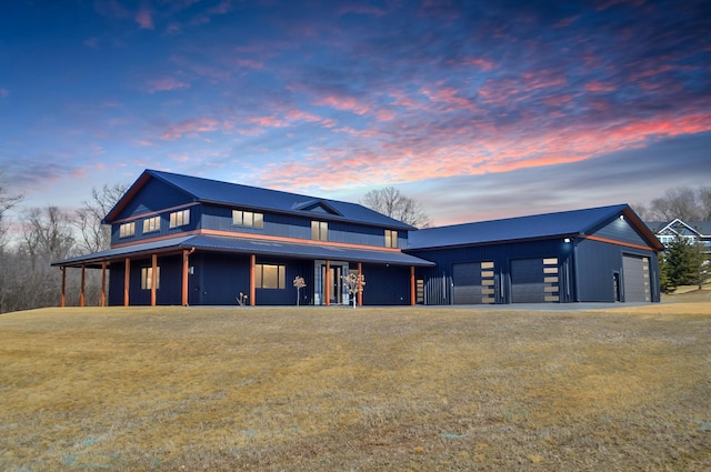 view of front of property featuring a lawn, metal roof, a garage, and an outdoor structure