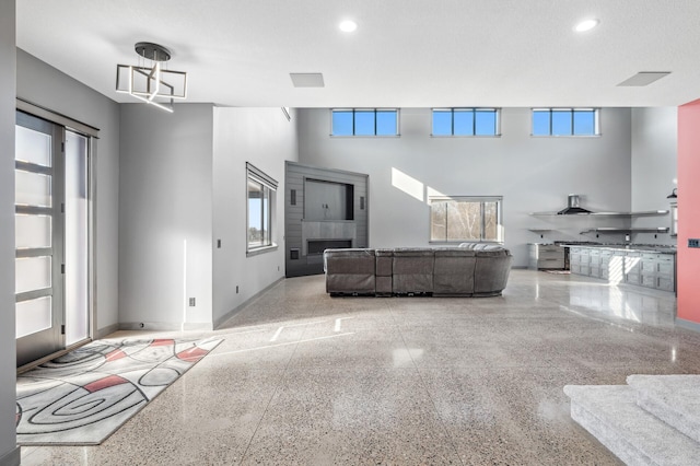living area with a towering ceiling, baseboards, speckled floor, and recessed lighting