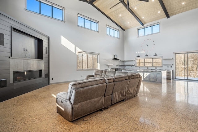 living room with high vaulted ceiling, wooden ceiling, speckled floor, a fireplace, and beamed ceiling