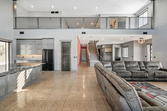 living room with light speckled floor, a towering ceiling, and visible vents
