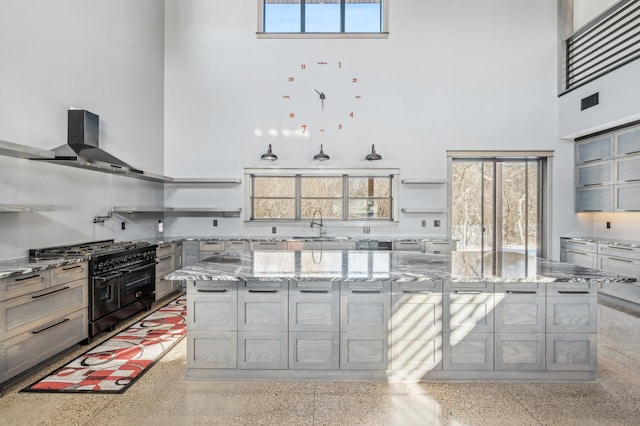 kitchen featuring open shelves, light speckled floor, and double oven range