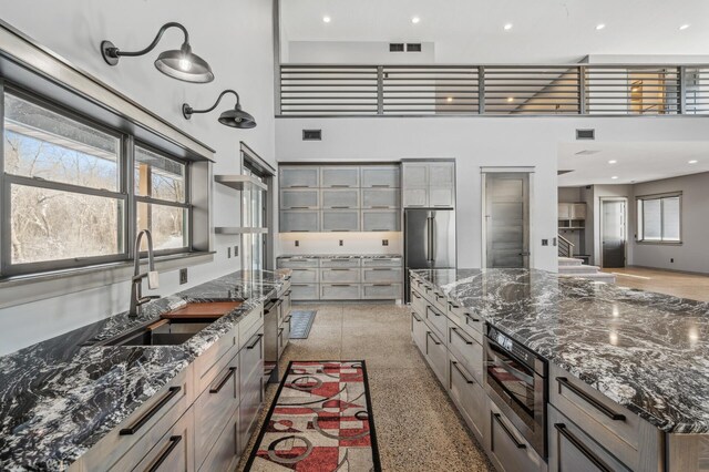 kitchen with visible vents, a towering ceiling, a sink, and high quality fridge