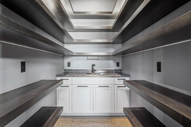 kitchen featuring light speckled floor, a sink, and white cabinetry