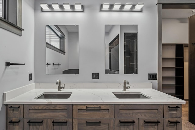 bathroom with double vanity, tiled shower, and a sink