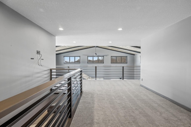 corridor with lofted ceiling, recessed lighting, carpet, baseboards, and a textured ceiling
