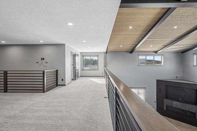 hall featuring an upstairs landing, a textured ceiling, baseboards, recessed lighting, and carpet floors