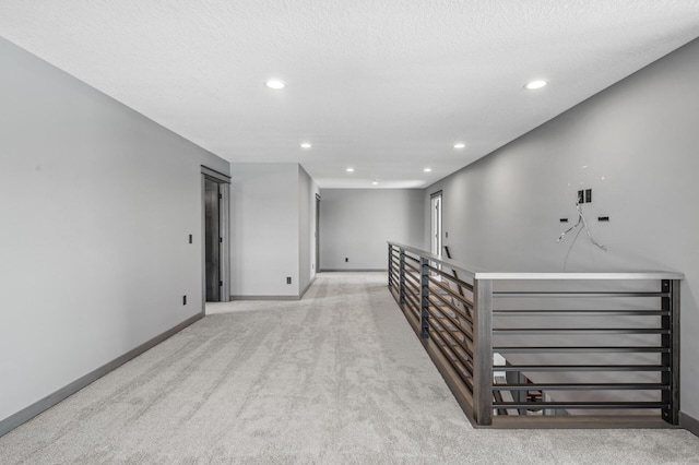 corridor with baseboards, recessed lighting, carpet, and a textured ceiling