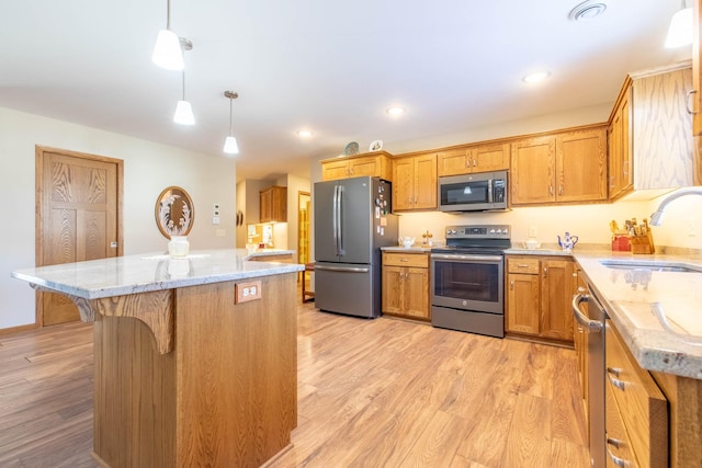 kitchen featuring hanging light fixtures, light wood-type flooring, stainless steel appliances, a center island, and sink