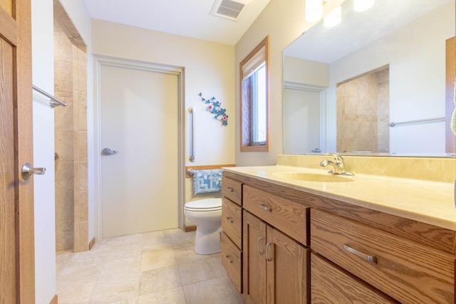 bathroom featuring tiled shower, vanity, toilet, and tile patterned flooring