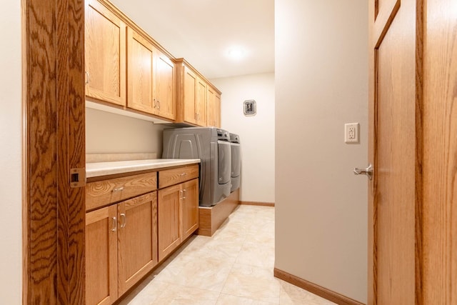 laundry area with separate washer and dryer and cabinets