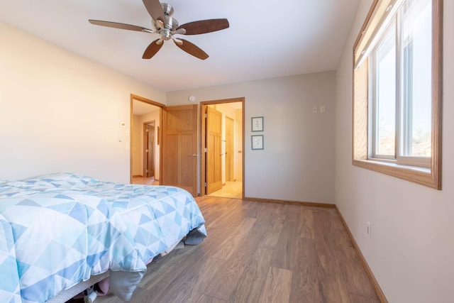 bedroom featuring light wood-style floors, baseboards, ceiling fan, and ensuite bathroom