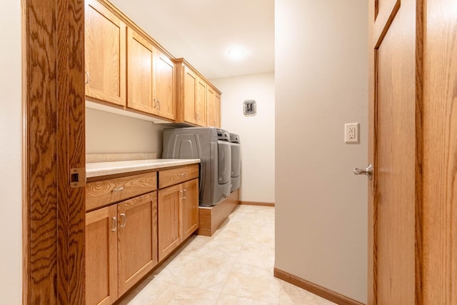 clothes washing area featuring washer and dryer, cabinet space, and baseboards
