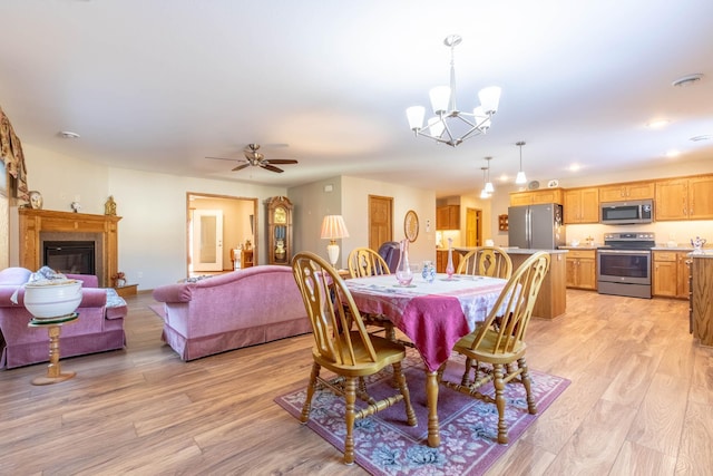 dining area with a chandelier, light wood finished floors, a glass covered fireplace, a ceiling fan, and recessed lighting