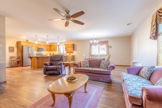 living area with light wood-style flooring, a ceiling fan, and a chandelier