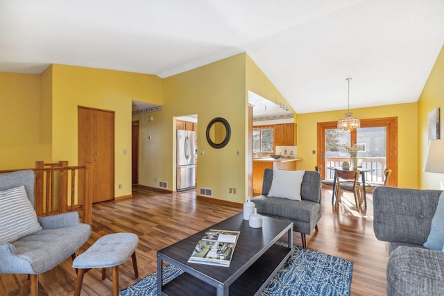 living room with lofted ceiling, hardwood / wood-style floors, and an inviting chandelier