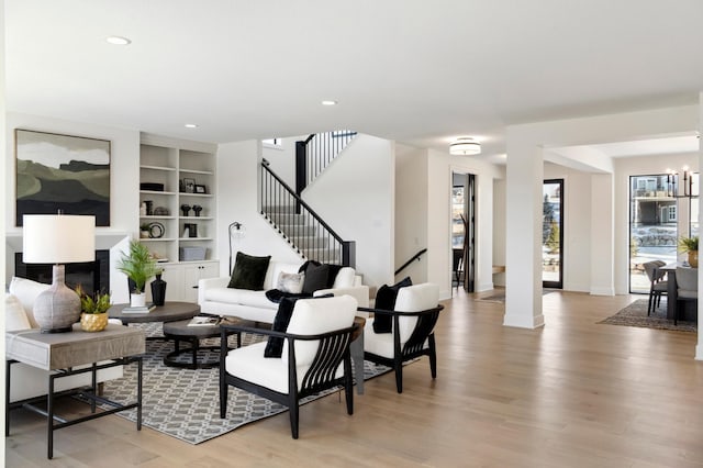 living room featuring ornate columns, light hardwood / wood-style floors, and built in shelves