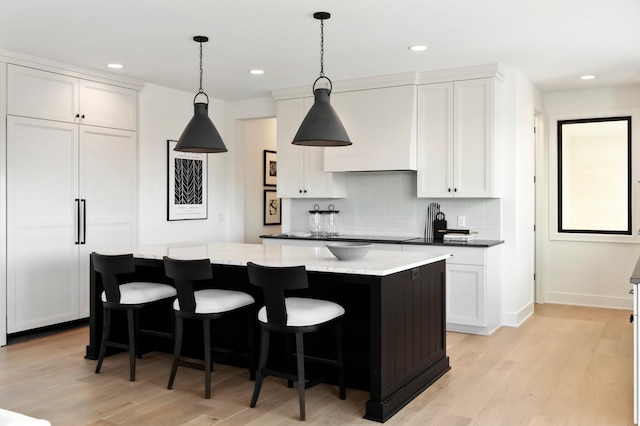 kitchen featuring light stone countertops, white cabinetry, a kitchen island, and decorative light fixtures