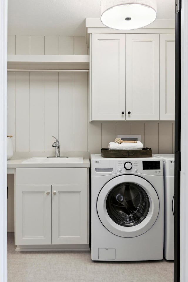 laundry room with independent washer and dryer, sink, and cabinets