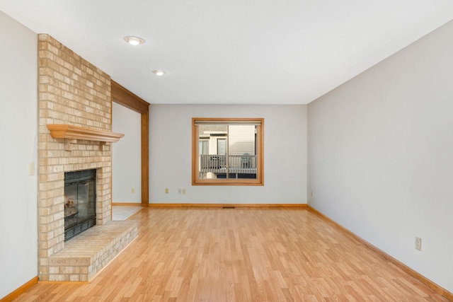 unfurnished living room featuring a fireplace and light hardwood / wood-style floors