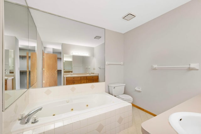 bathroom with vanity, toilet, and tiled tub