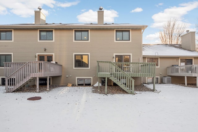 snow covered rear of property with central AC unit and a deck