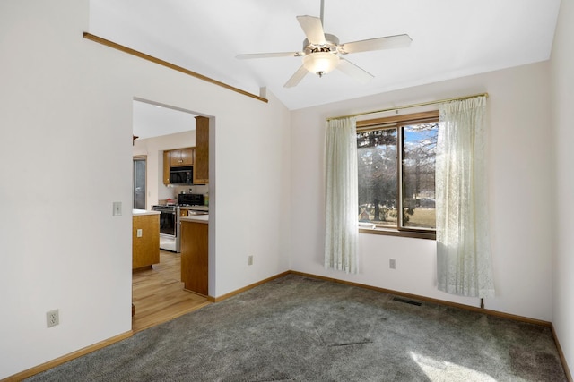 spare room with vaulted ceiling, light colored carpet, and ceiling fan