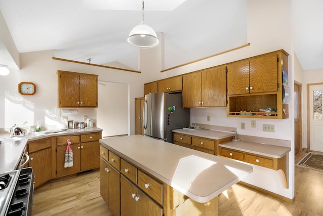 kitchen featuring sink, light hardwood / wood-style flooring, stainless steel appliances, a center island, and decorative light fixtures