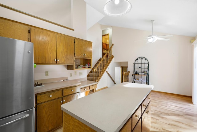 kitchen featuring lofted ceiling, stainless steel fridge, ceiling fan, a center island, and light hardwood / wood-style floors