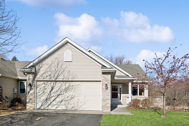 view of front of property featuring aphalt driveway, brick siding, a shingled roof, an attached garage, and a front yard