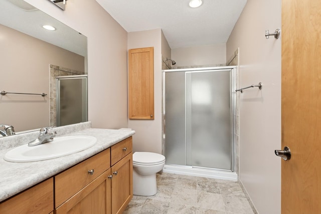 bathroom featuring toilet, a stall shower, and vanity