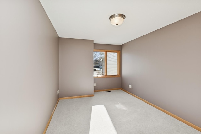 spare room featuring carpet, visible vents, and baseboards