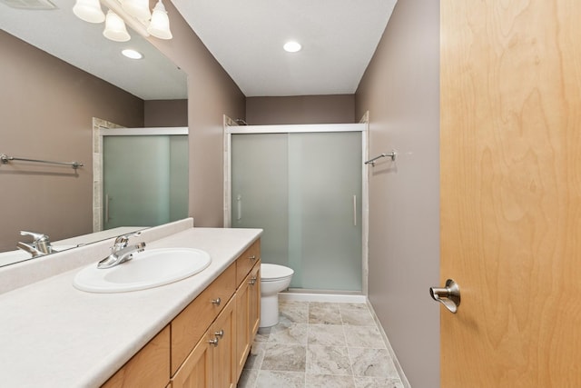 bathroom with a stall shower, vanity, toilet, and baseboards