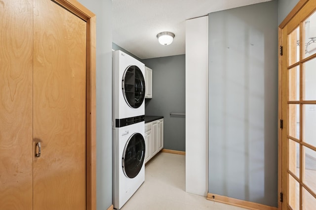 clothes washing area with cabinet space and stacked washer / dryer