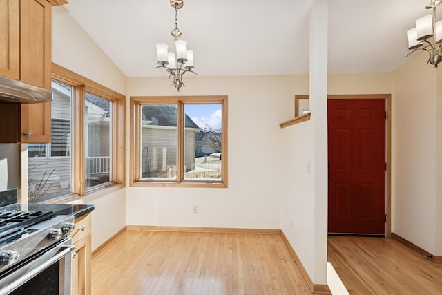 kitchen with baseboards, light wood-type flooring, gas range, and an inviting chandelier