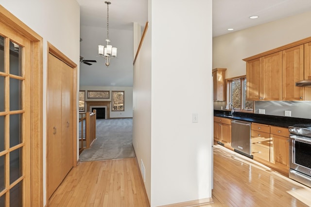 hall with light wood finished floors, a towering ceiling, an inviting chandelier, a sink, and baseboards