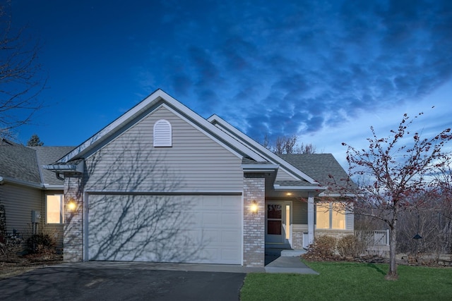 view of front of home with driveway, a shingled roof, an attached garage, a front lawn, and brick siding