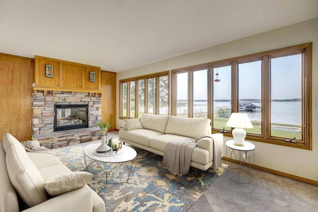 carpeted living area with a stone fireplace, baseboards, and a water view
