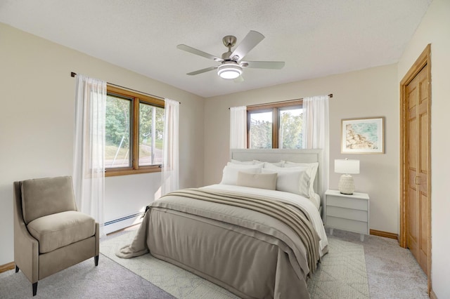 bedroom featuring a baseboard radiator, multiple windows, baseboards, and light carpet