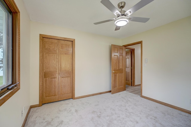 unfurnished bedroom featuring ceiling fan, light carpet, a closet, and baseboards