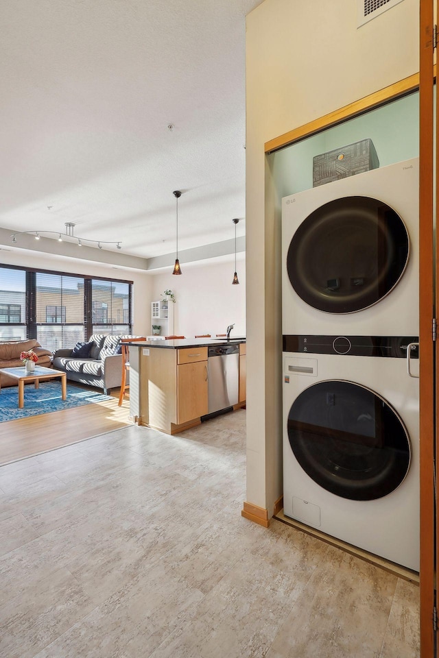 washroom with stacked washing maching and dryer and rail lighting