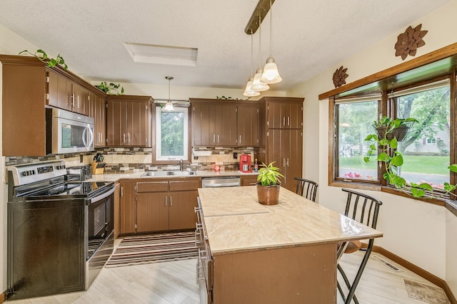 6645 Lancaster Ln N, Maple Grove, MN 55369 - kitchen featuring stainless steel appliances, light wood-type flooring, light countertops, backsplash, and a kitchen island