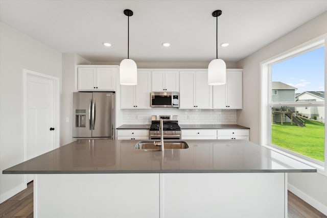 kitchen featuring stainless steel appliances, a center island with sink, and white cabinets