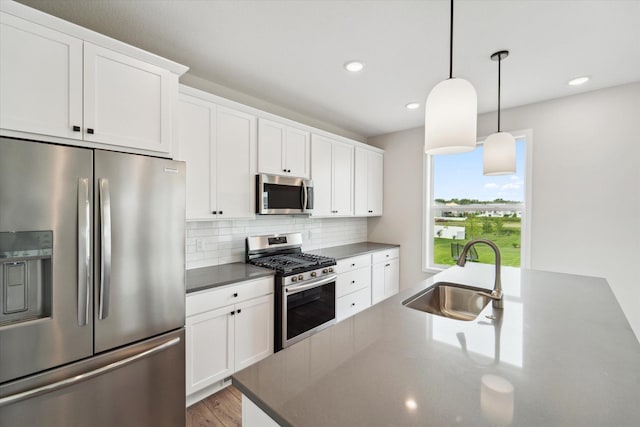 kitchen with pendant lighting, sink, appliances with stainless steel finishes, white cabinets, and decorative backsplash