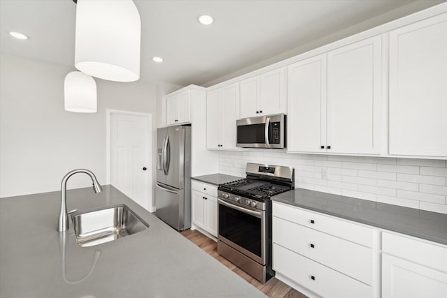 kitchen with white cabinetry, stainless steel appliances, sink, and hanging light fixtures