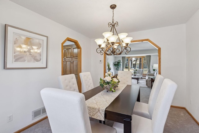 carpeted dining space featuring a chandelier